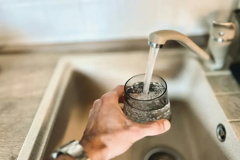 Glass being filled with tap water at a kitchen sink